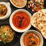 Overhead spread of Indian curries, biryani, fried rice, spicy paneer and freshly baked naan at Food Exchange Aerocity Delhi